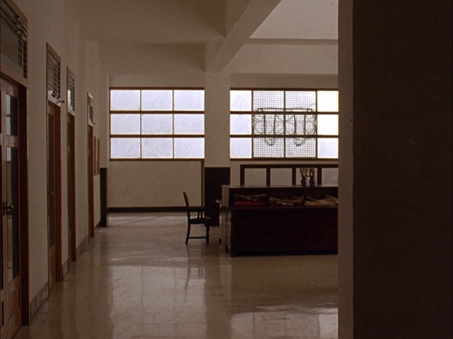 a quiet corridor inside a government administration office in India, frosted windows and teak doors, morning light