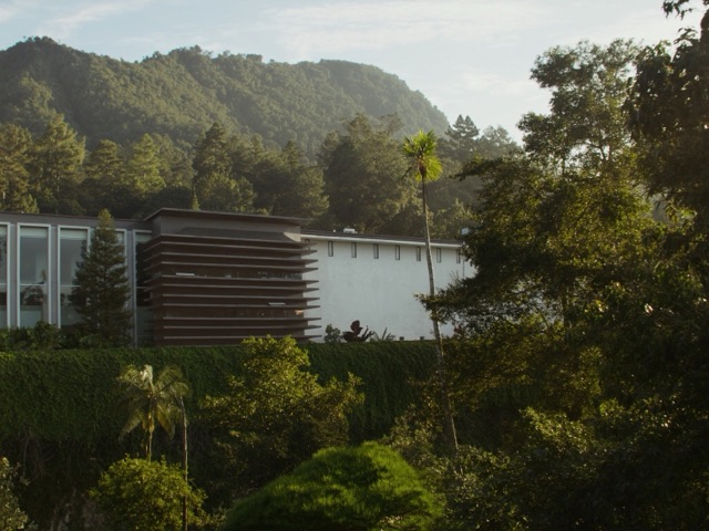 modern government technology building in Kuching, Sarawak, Malaysia with tropical greenery and rainforest hills behind it, afternoon light, wide angle